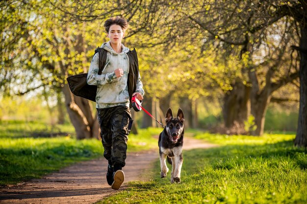 Un ragazzo con un cane cammina nel parco in una soleggiata serata primaverile corre lungo la strada Amicizia dell'uomo e dello stile di vita sano degli animali