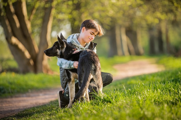 Un ragazzo con un cane cammina nel parco in una soleggiata serata primaverile si siede sull'erba il cane obbedisce all'ordine dare una zampa Amicizia dell'uomo e dello stile di vita sano degli animali