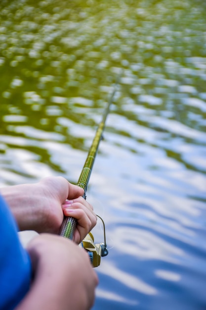 Un ragazzo con un cappello leggero sta pescando su un fiume pittoresco in estate