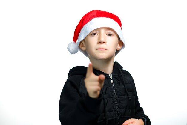 Un ragazzo con un cappello rosso da Babbo Natale punta il dito indice verso la telecamera