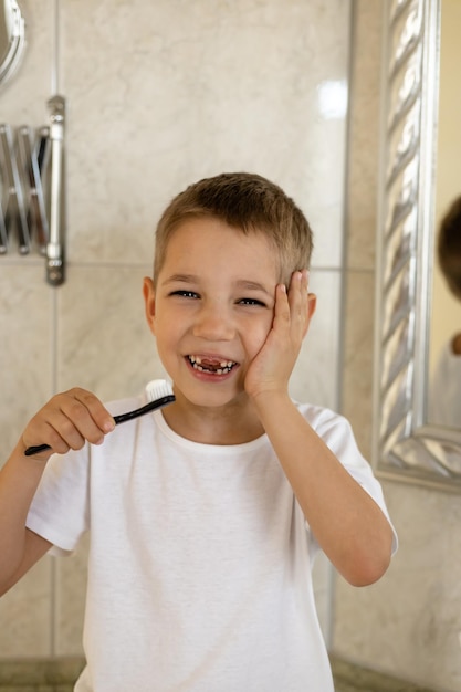 Un ragazzo con un dente cattivo si lava i denti in bagno mal di denti