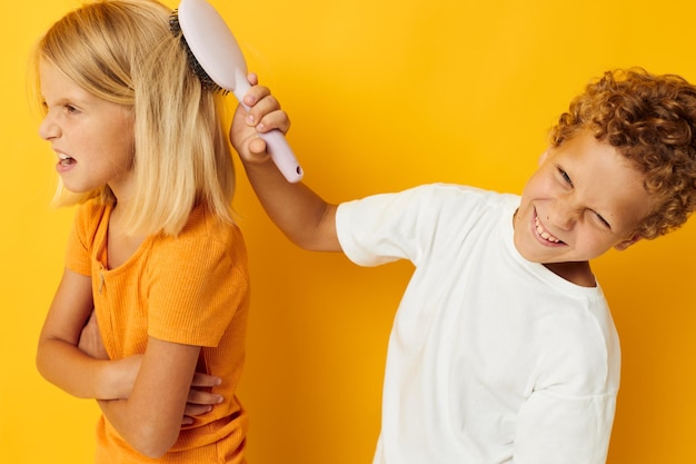 Un ragazzo con un pettine che pettina uno sfondo giallo dei capelli di una ragazza