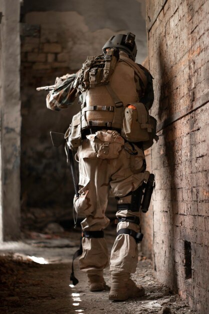 un ragazzo con un'uniforme militare americana in un vecchio corridoio abbandonato si muove con una pistola gioco sportivo softair