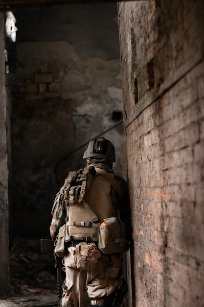 un ragazzo con un'uniforme militare americana in un vecchio corridoio abbandonato si muove con una pistola softair sport gioco