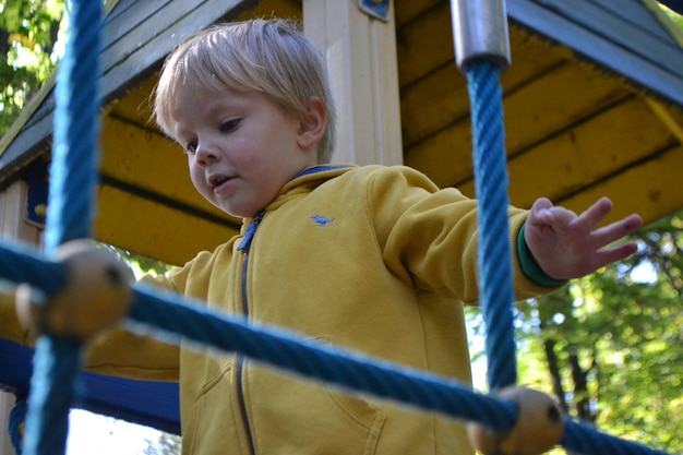 Un ragazzo con una giacca gialla gioca in un parco giochi.