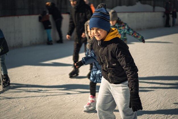 Un ragazzo con una giacca nera pattina su una pista di pattinaggio con un uomo con un cappello blu.