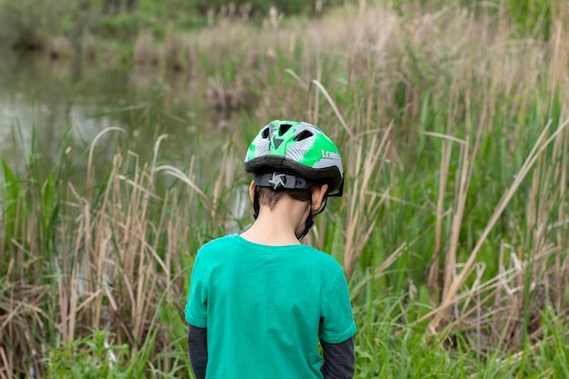 Un ragazzo con una maglietta verde e un casco verde cammina in un campo di erba alta.