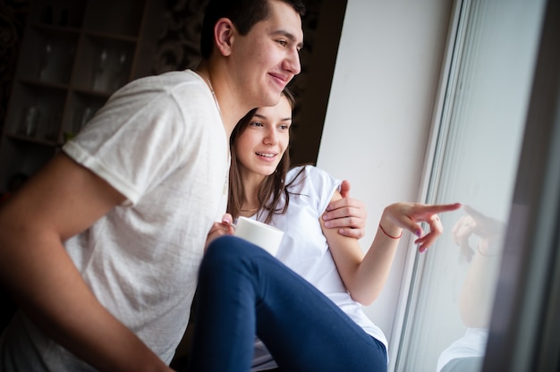 Un ragazzo con una ragazza che beve caffè vicino alla finestra