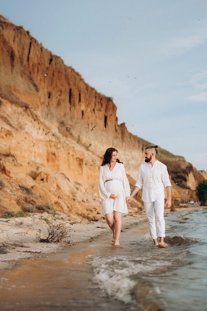 Un ragazzo con una ragazza in abiti bianchi in riva al mare