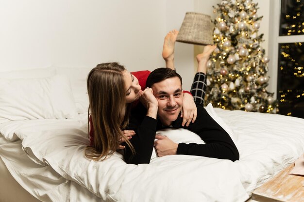 Un ragazzo con una ragazza in pigiama che si abbraccia sul letto la sera. sera di natale.