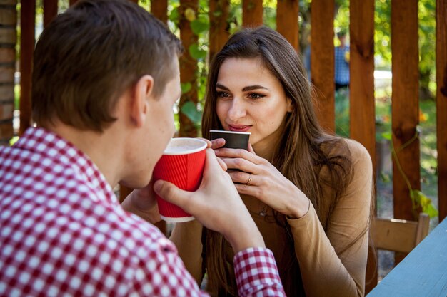 Un ragazzo e una ragazza bevono un caffè nel parco sulla terrazza di un bar