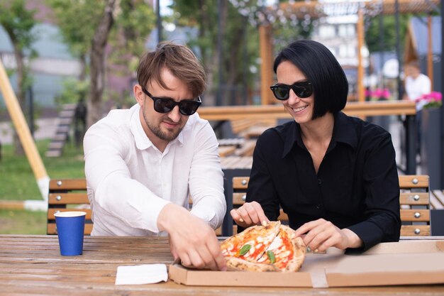 Un ragazzo e una ragazza condividono una pizza in una scatola