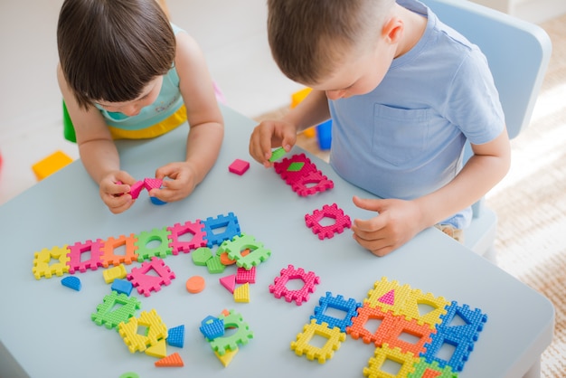 Un ragazzo e una ragazza raccolgono un puzzle morbido al tavolo