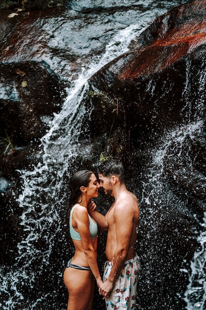 Un ragazzo e una ragazza si accoppiano insieme sotto una piccola cascata