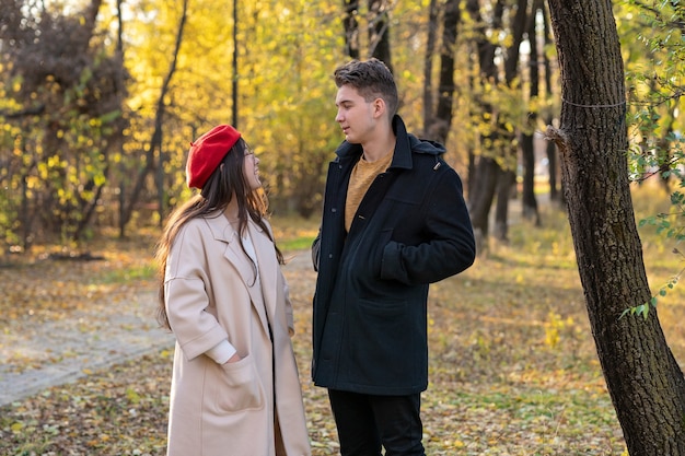 Un ragazzo e una ragazza sono in piedi in un parco autunnale e parlano Coppia che cammina