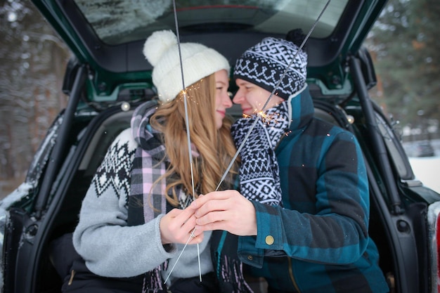 un ragazzo e una ragazza sono seduti nel bagagliaio di un'auto, in una coperta con le stelle filanti