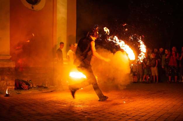 Un ragazzo fa uno spettacolo di fuoco per strada di notte intorno a una folla di persone
