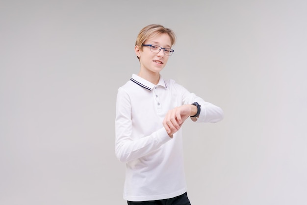 Un ragazzo felice con gli occhiali e una maglietta guarda il suo orologio o il suo fitness tracker