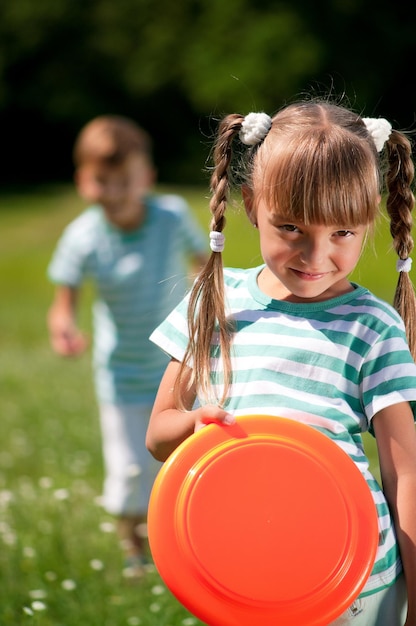 Un ragazzo felice e una ragazzina che giocano a frisbee su un prato in una giornata di sole