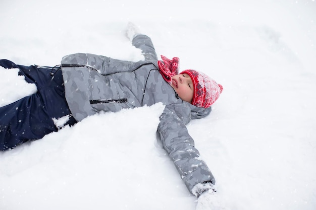 Un ragazzo felice giace nella neve e si gode il tempo