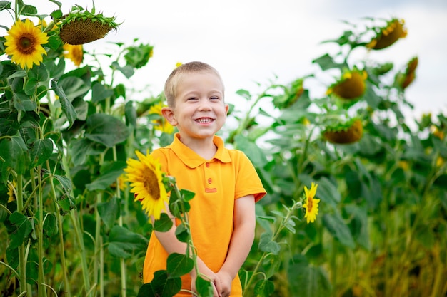 Un ragazzo felice si trova in un campo di girasoli