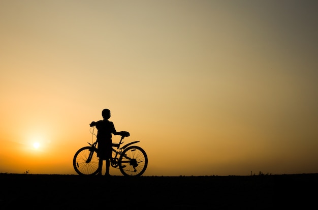 Un ragazzo fitness silhouette alba ciclismo concetto di allenamento allenamento.