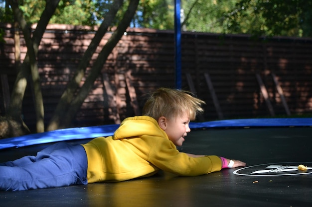 Un ragazzo giace su un trampolino in un giardino.