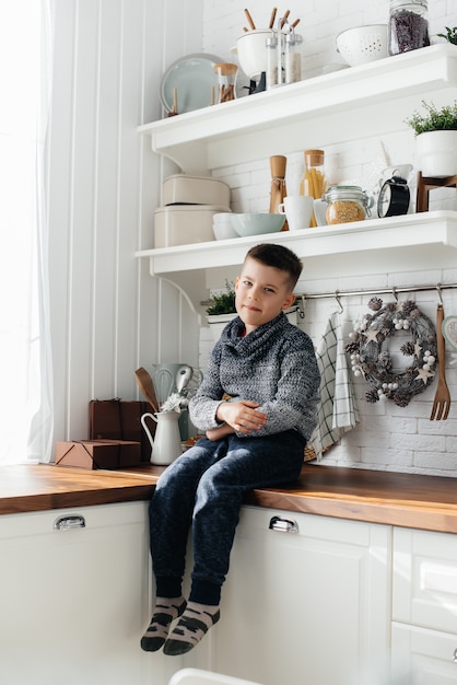 Un ragazzo gioca e fa colazione in cucina. Felicità. Una famiglia.