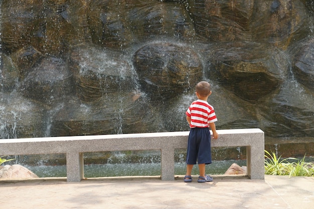 Un ragazzo guarda la cascata nel giardino