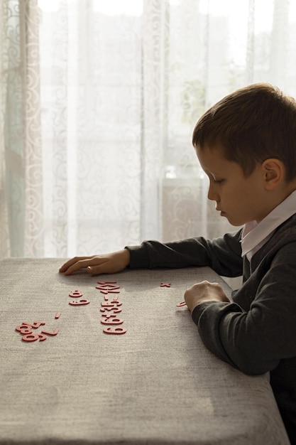 Un ragazzo impara a contare alla sua scrivania usando numeri di plastica