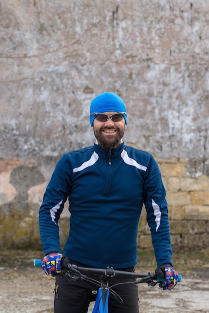 Un ragazzo in abbigliamento sportivo che guida vestiti su una mountain bike su un muro di cemento di mattoni vintage