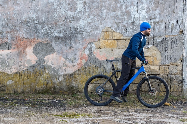 Un ragazzo in abiti sportivi in sella a una moderna mountain bike su un muro di cemento in mattoni d'epoca