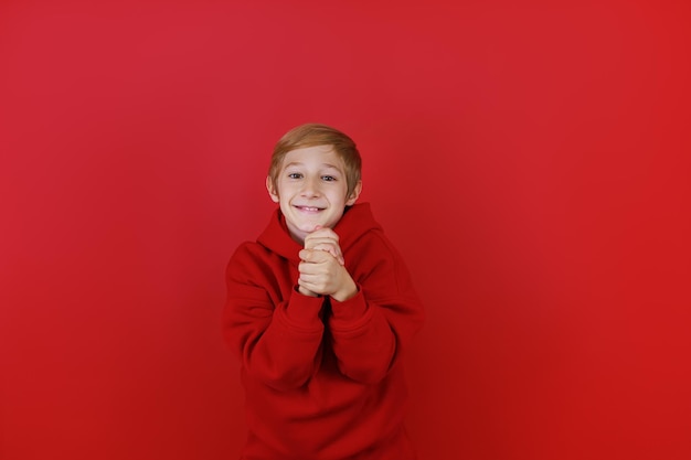 Un ragazzo in abito rosso e su sfondo rosso incrociò le mani davanti a lui