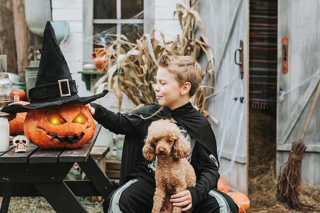Un ragazzo in costume da scheletro con un cane sotto il portico di una casa decorata per celebrare una festa di Halloween