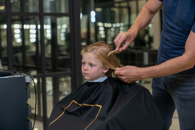 Un ragazzo in un parrucchiere ottiene un taglio di capelli e lo styling