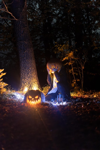 Un ragazzo in una foresta oscura con una zucca in testa