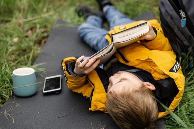 Un ragazzo legge un libro in una radura