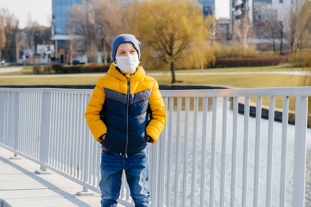 Un ragazzo si trova su uno sfondo grigio in una maschera durante una quarantena con spazio libero. Quarantena nella maschera