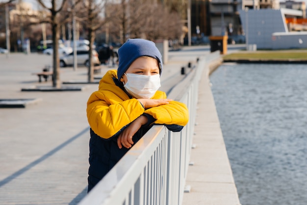 Un ragazzo si trova su uno sfondo grigio in una maschera durante una quarantena con spazio libero. Quarantena nella maschera.