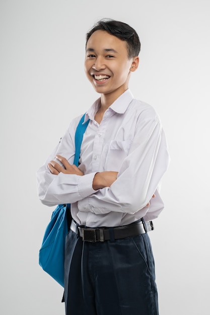 Un ragazzo sorridente che indossa un'uniforme scolastica e porta uno zaino con le mani incrociate