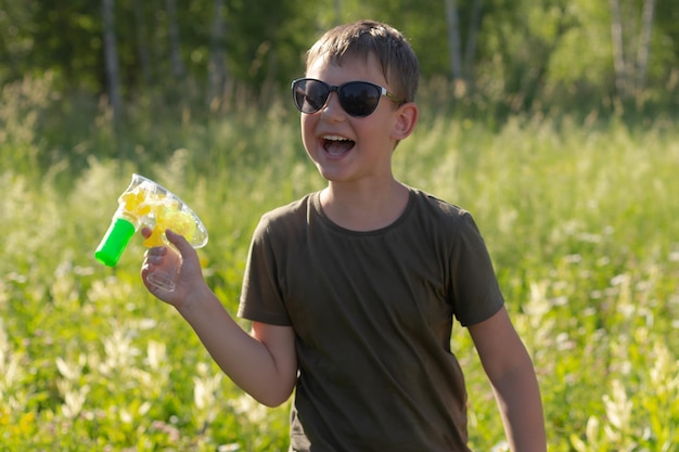 Un ragazzo sorridente con una pistola per sapone in mano nella natura Emozioni positive Intrattenimento