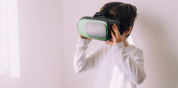 Un ragazzo sta giocando occhiali vr su un muro bianco copyspace Un articolo sui gadget moderni Un articolo sulle tecnologie moderne