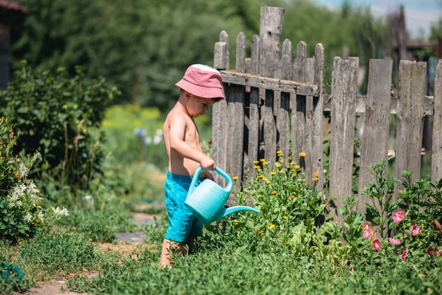 Un ragazzo sta innaffiando i fiori nel giardino.