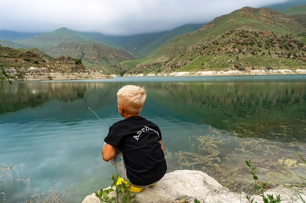 Un ragazzo sta pescando sul lago di montagna Gizhgit nella regione di KabardinoBalkaria Elbrus in Russia giugno 2021