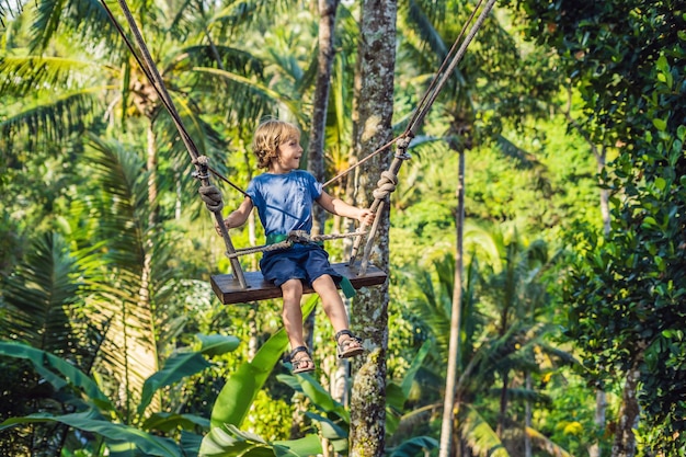 Un ragazzo su un'altalena sopra la giungla, Bali.