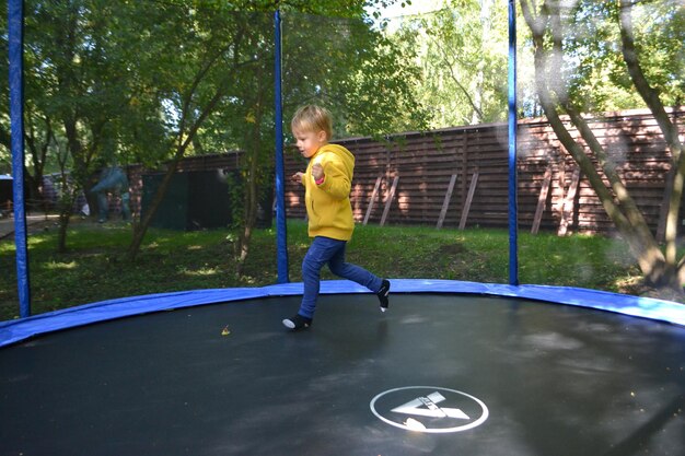 Un ragazzo su un trampolino nel giardino foto di alta qualità