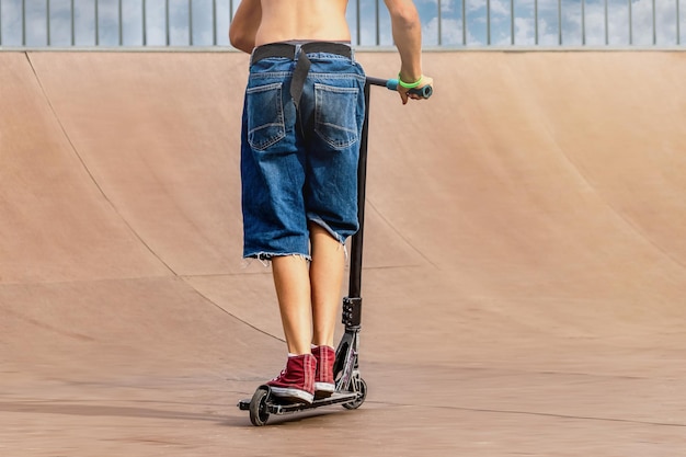 Un ragazzo su uno scooter e in uno skate park fa salti e acrobazie incredibili Salti estremi su uno scooter Il concetto di uno stile di vita sano e del tempo libero sportivo