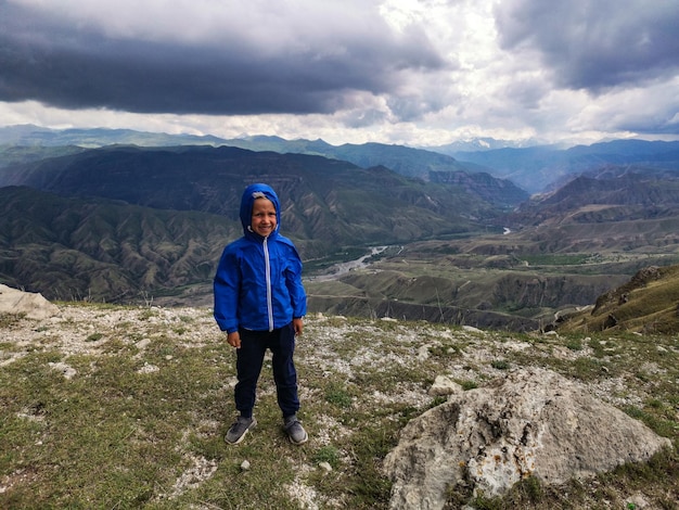 Un ragazzo sullo sfondo di una vista mozzafiato sulle montagne durante un temporale in Daghestan Caucaso Russia