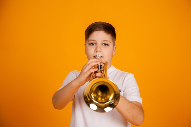 Un ragazzo suona la tromba un bellissimo ragazzo adolescente suona uno strumento musicale a tromba