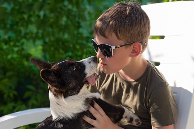 Un ragazzo tiene in braccio un cane di razza Welsh corgi Pembroke Vita domestica